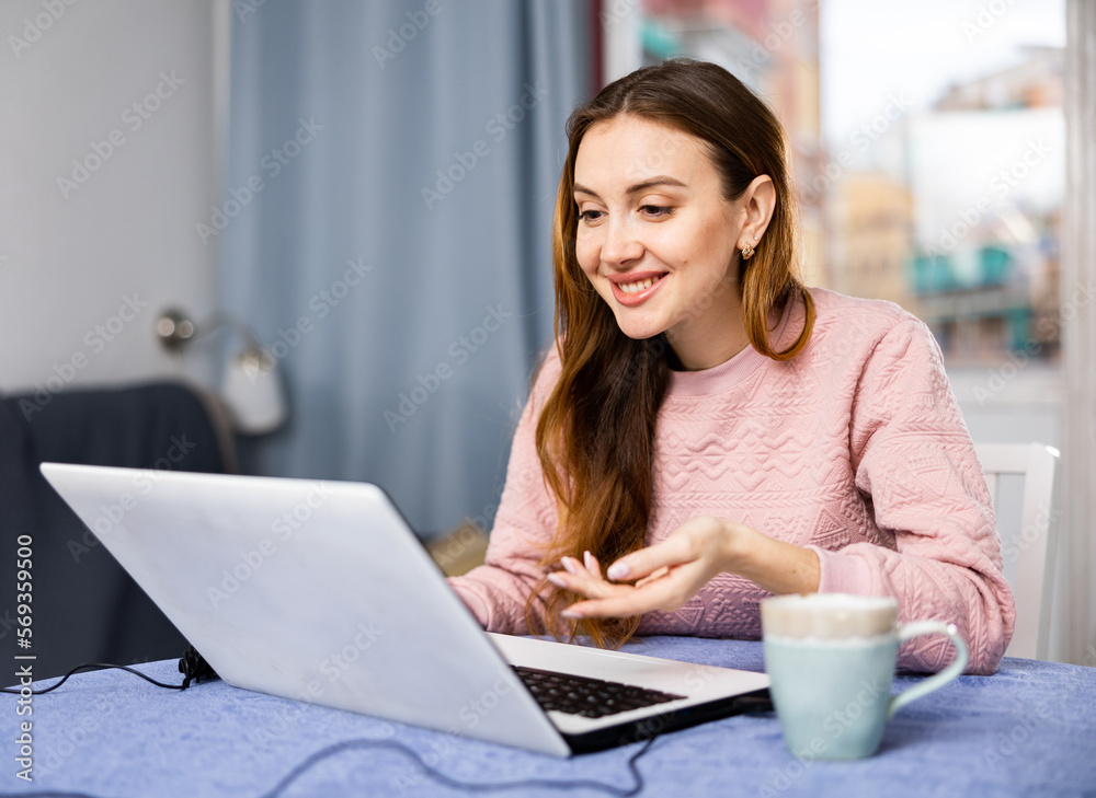 Young woman communicates over internet using laptop at home
