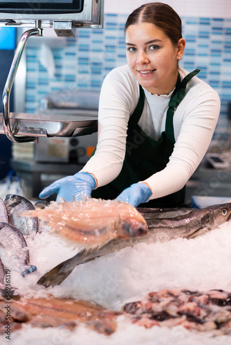 Smiling salesclerk demonstrating scaldfish in fish store. High quality photo