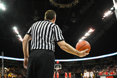 Basketball Referee Holding an Orange Basketball in a Large Sports Arena