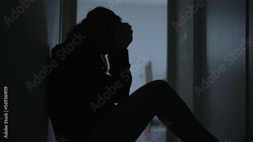 Lonely woman sitting at home alone on floor covering face in shame and regret. Person suffering from trauma feelng anxiety and depression photo