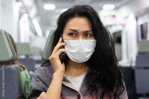 Woman traveler in a protective mask talking on a mobile phone in a subway car