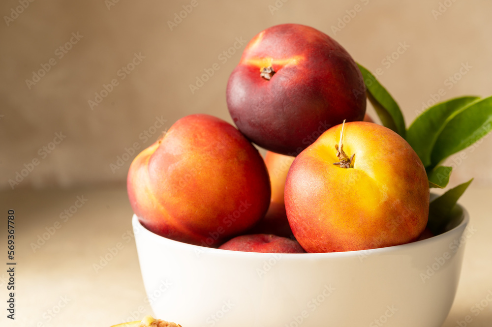 Closeup nectarine peaches, fresh red fruits in a bowl. Neutral background. Closeup nectarine peaches, fresh red fruits in a bowl. Neutral background.