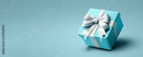 Blue gift box with silver ribbon bow on blue background.  Illustration AI © hd3dsh
