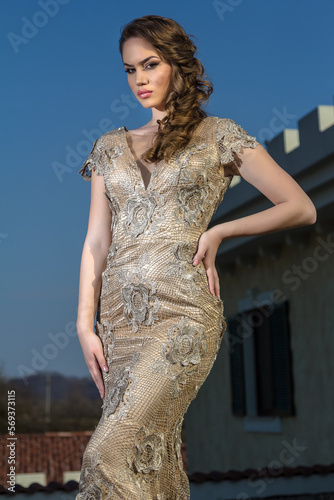 Young woman in a golden dress is standing