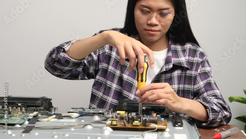 Wallpaper Mural Young female technician working on computer parts with a screw driver tool on desk at home. Torontodigital.ca