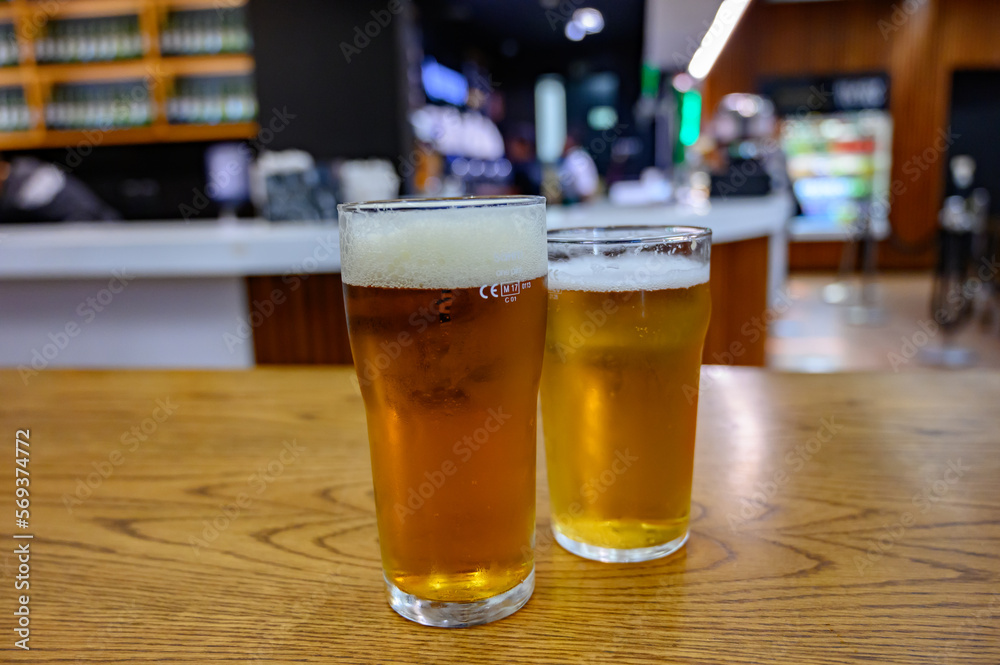 Fresh draught lager or IPA beer is glass served in indoor cafe close up, pint of beer Fresh draught lager or IPA beer is glass served in indoor cafe close up, pint of beer