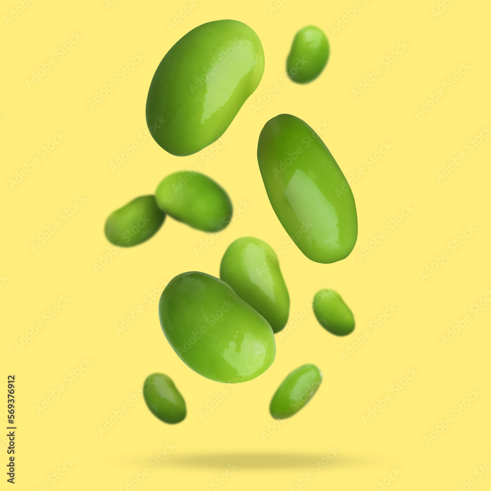 Delicious cooked soy beans falling on pale yellow background. Edamame Delicious cooked soy beans falling on pale yellow background. Edamame