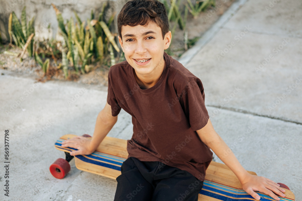 Portrait of teen boy sitting on skateboard