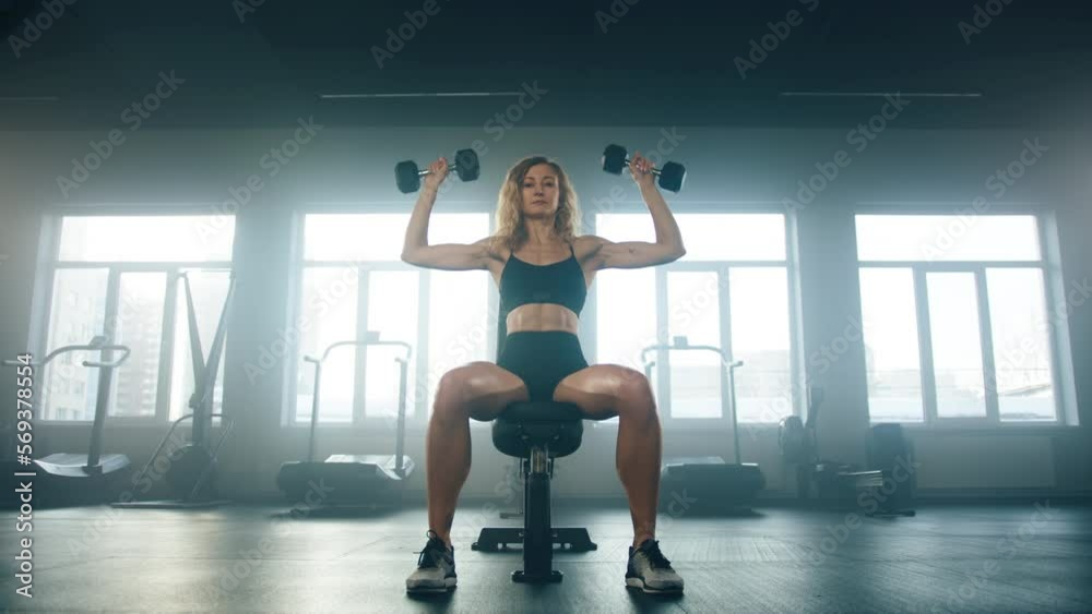 Female athlete performing high intensity strength training. Close-up view of caucasian sportswoman using dumbbells to build lean muscle mass at gym studio. High quality 4k footage Female athlete performing high intensity strength training. Close-up view of caucasian sportswoman using dumbbells to build lean muscle mass at gym studio. High quality 4k footage