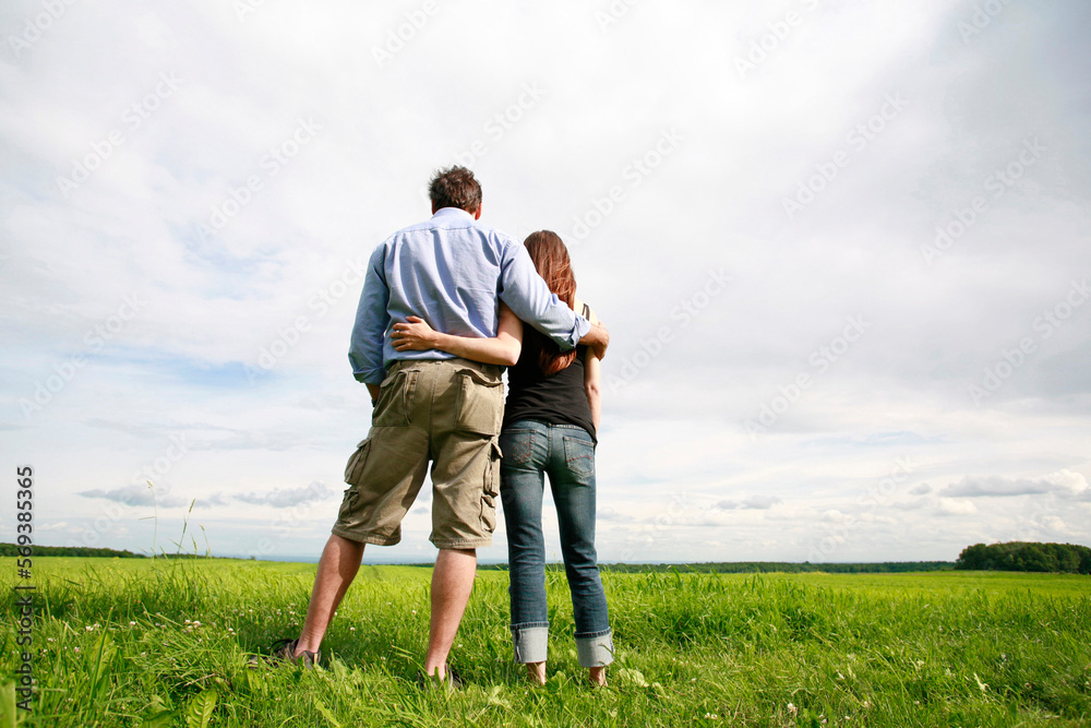 Rear view of young couple hugging and overlooking farmland. Rear view of young couple hugging and overlooking farmland.