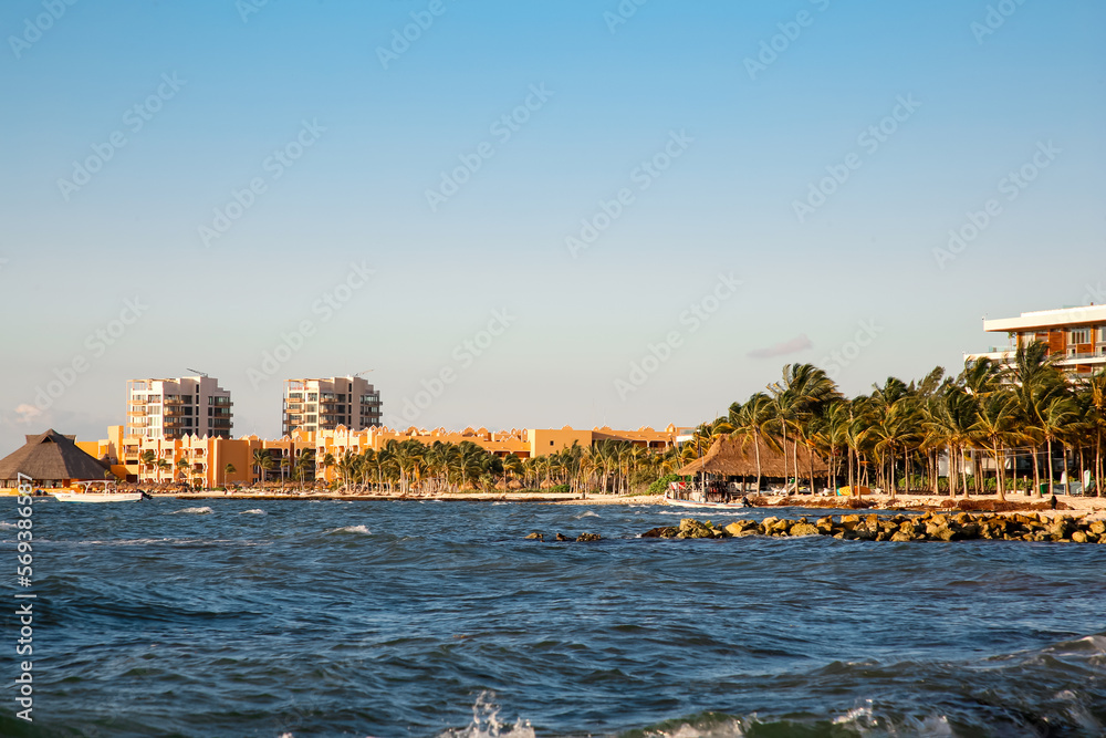 Picturesque view of sea coast, palm trees and distant resort on sunny day
