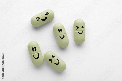 Antidepressant pills with emotional faces on white background, top view