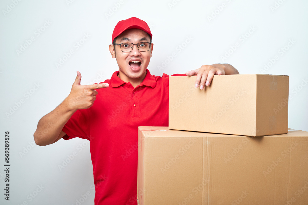 Confident asian courier man in red uniform encourage call service, showing and pointing at cardboard box while lean on it Confident asian courier man in red uniform encourage call service, showing and pointing at cardboard box while lean on it
