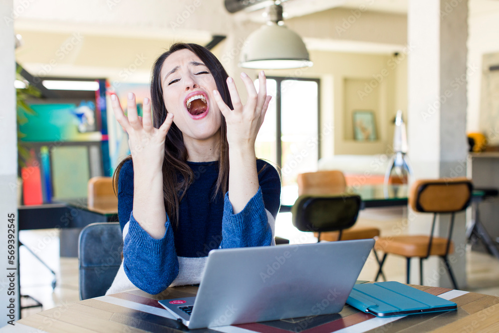 Obraz premium young pretty woman looking desperate, frustrated and stressed. telecommuting concept