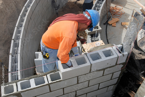 Mason installing a structural block retaining wall