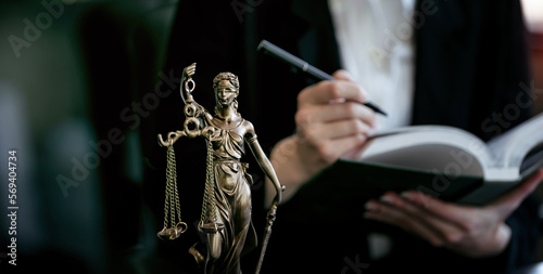 Statue Of Lady Justice, lawyer holding book in background.