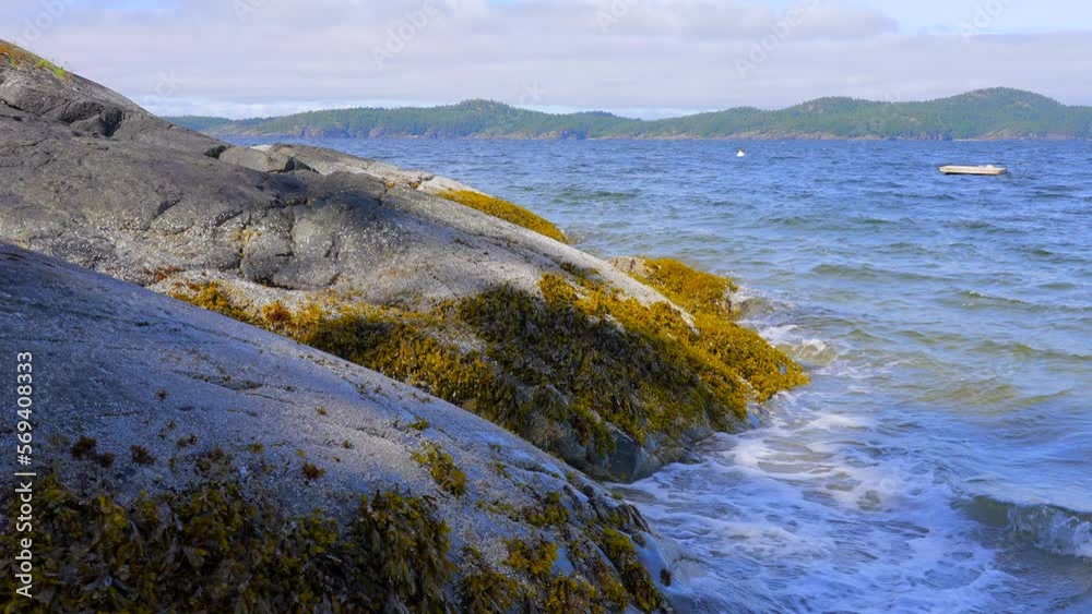 Establishing shot of ocean beach with rocks and pebbles in slow motion at summer day in Vancouver, Canada, North America. Day time on September 2022. Still camera. ProRes 422 HQ. Establishing shot of ocean beach with rocks and pebbles in slow motion at summer day in Vancouver, Canada, North America. Day time on September 2022. Still camera. ProRes 422 HQ.