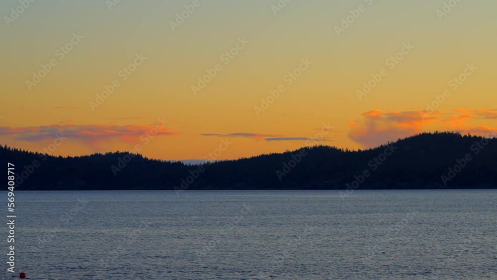 Establishing shot of ocean sunset over mountains in slow motion at summer day in Vancouver, Canada, North America. Evening time on September 2022. Still camera. ProRes 422 HQ. Establishing shot of ocean sunset over mountains in slow motion at summer day in Vancouver, Canada, North America. Evening time on September 2022. Still camera. ProRes 422 HQ.