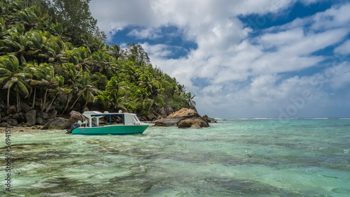 Bild auf Leinwand The boat is moored off the coast of a tropical island overgrown with palm trees