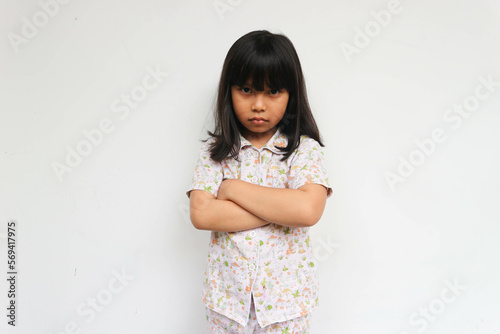 Asian little girl with pajama is show angry expression crossed hand looking at camera on the white background, sign and gesture concept
