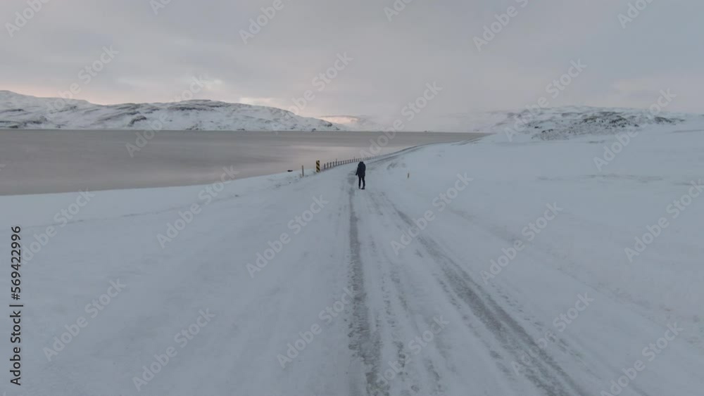 Dolly forward, girl slowly walking on empty slippery road, winter scenery. Dolly forward, girl slowly walking on empty slippery road, winter scenery.