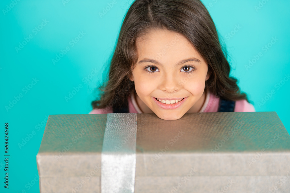 cheerful girl with birthday gift isolated on blue. girl with birthday gift in studio. cheerful girl with birthday gift isolated on blue. girl with birthday gift in studio.