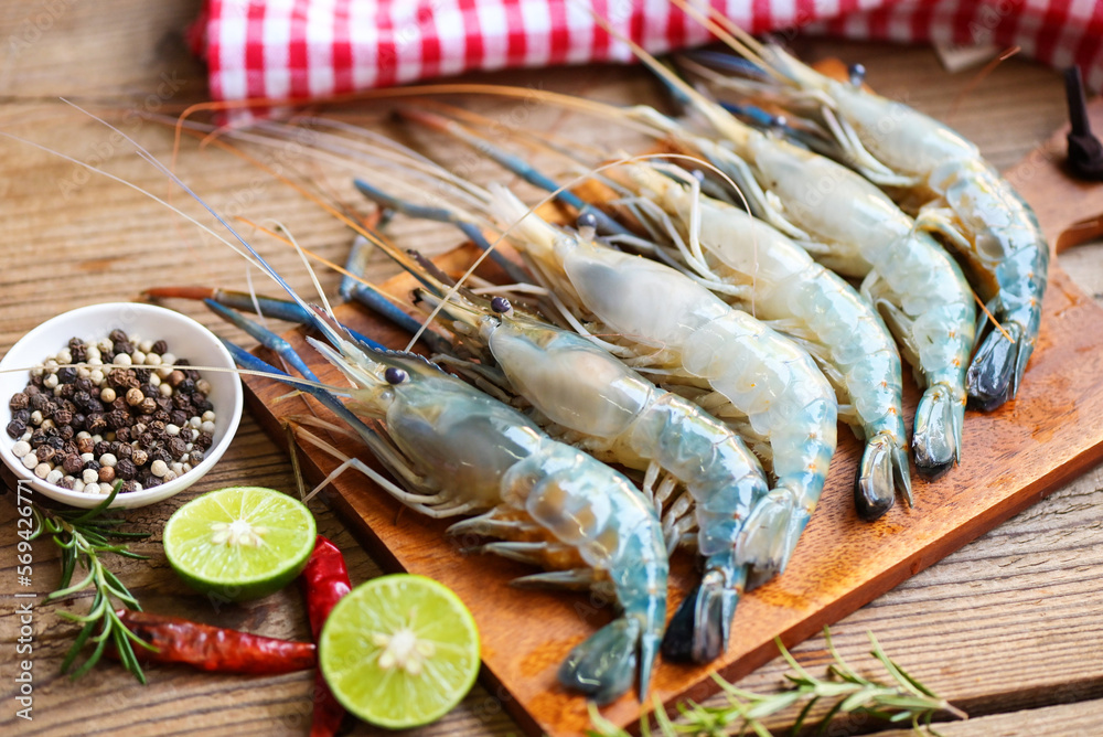 fresh shrimps prawns seafood shelfish with herb and spices chilli pepper lemon lime rosemary, raw shrimp on plate background for cooking food