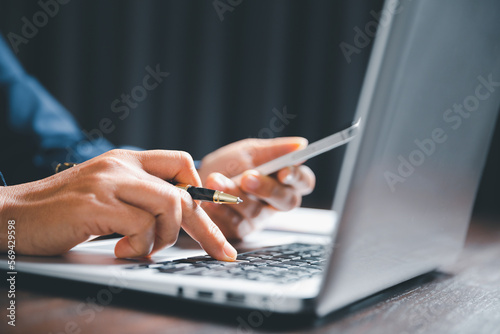 Closeup of businesswoman typing on laptop computer while sitting on table in office for design work, insert icons or business technology symbols. selective focus on hand. female online working on desk