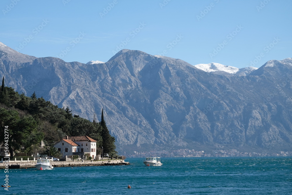 Boka Kotor Bay of the Adriatic Sea in Montenegro.  Houses and boats against the backdrop of snow-capped mountains.