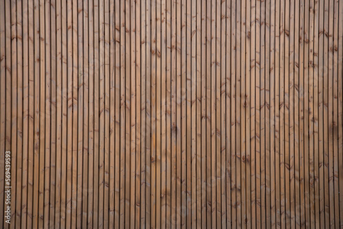 brown natural wooden background with wall of small vertical wood boards on a horizontal facade