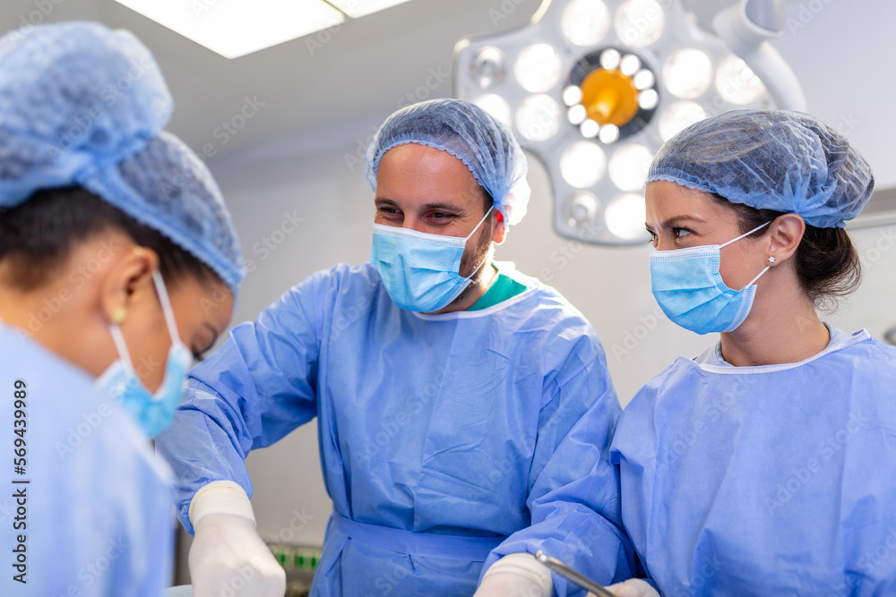 Portrait of team of multiethnic surgeons at work in a operation theatre. Several doctors surrounding patient on operation table during their work. Team surgeons at work in operating room. Portrait of team of multiethnic surgeons at work in a operation theatre. Several doctors surrounding patient on operation table during their work. Team surgeons at work in operating room.