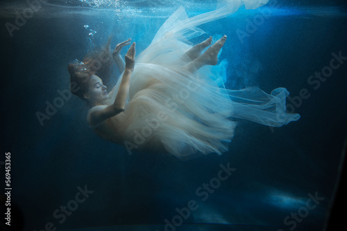 Young beautifull caucasian woman in dress under water