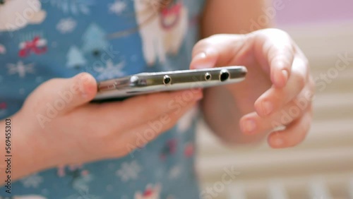 The child holds the phone, presses the buttons on the end of the smartphone, takes a screenshot, searches for information on the Internet.