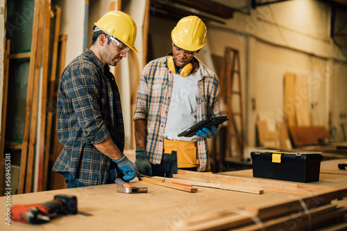 Two Carpenter working on wood craft at workshop to produce construction material or wooden furniture. The young carpenter use professional tools for crafting. DIY maker and carpentry work concept.