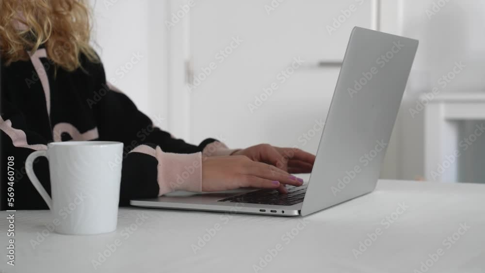 Young woman working on her laptop from home while drinking a cup of coffee Young woman working on her laptop from home while drinking a cup of coffee