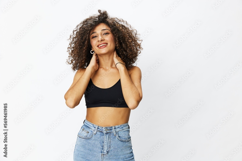 Beautiful woman with curly afro hair posing on a white isolated background smile happiness in jeans and black top emotion, hand signs, copy space