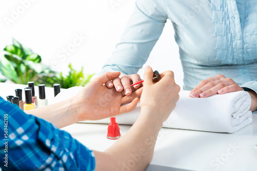 Manicurist working with client's nails at table