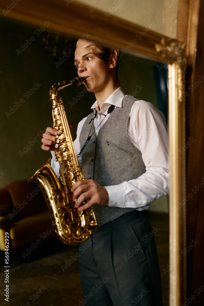 Naklejka premium Young man playing saxophone in reflection of mirror at home