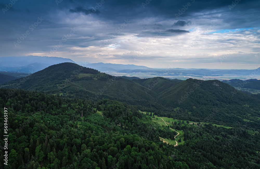 Obraz premium Aerial view of a beautiful landscape from Bucegi mountains in Romania, with forest green trees and cloudy sky. Travel to Romania.