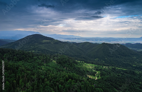 Aerial view of a beautiful landscape from Bucegi mountains in Romania, with forest green trees and cloudy sky. Travel to Romania.
