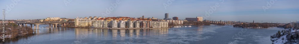 Panorama, view from the hill Ormberget over the districts Essingen islands and Kungsholmen, waterfront apartments at a bay of the Mälaren se and bridges, a sunny snowy winter day in Stockholm