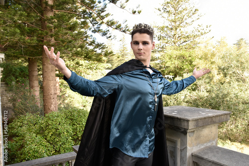 Close up portrait of handsome brunette man wearing fantasy medieval prince costume with golden crown and romantic silk shirt. historical castle location background. photo