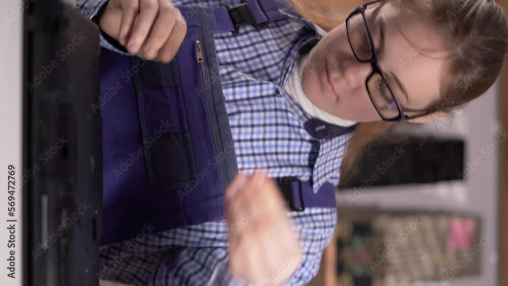 Young woman disassembles a laptop. Laptop disassembling in repair shop, close-up. Computer service and repair. Vertical video Young woman disassembles a laptop. Laptop disassembling in repair shop, close-up. Computer service and repair. Vertical video