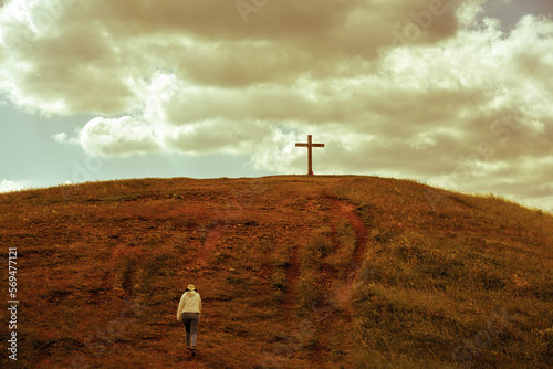 Person walking towards a cross on the hill photo
