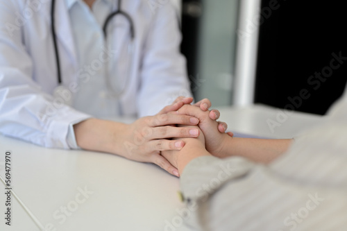 A professional female doctor holding a patient s hands  supporting and reassuring