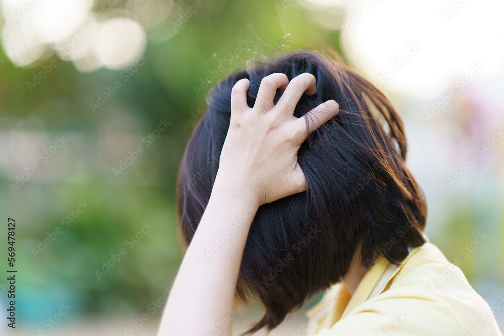 Woman scratching her head due to yeast infection or dandruff on her scalp. Health care concept.