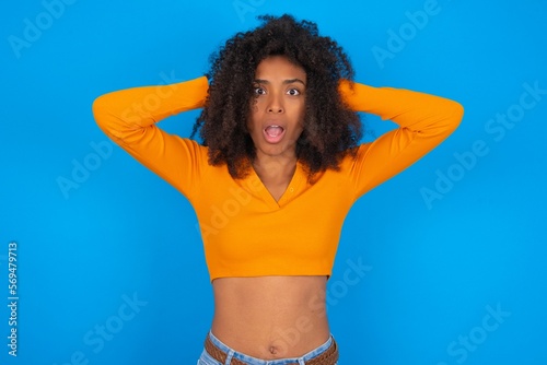 Cheerful overjoyed young beautiful brunette woman wearing colourful dress over white wall reacts rising hands over head after receiving great news.