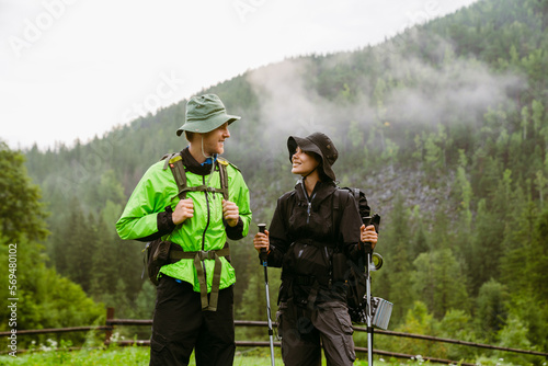 Multiethnic tourist couple smilimg at each other during hiking in mountains photo