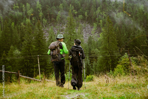 Back view of tourist couple hiking in mountain forest