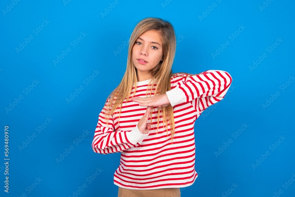 caucasian teen girl wearing striped shirt over blue studio background ...